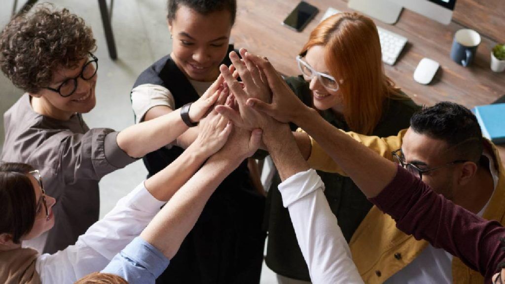 Team with hands all coming together in the middle of a circle.
