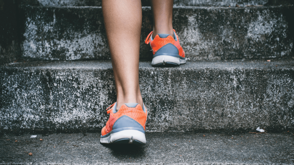 Bottom half of person walking upstairs. Focused on their sneakers.