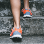 Bottom half of person walking upstairs. Focused on their sneakers. 