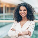 Woman with folded arms smiling and staring to camera.