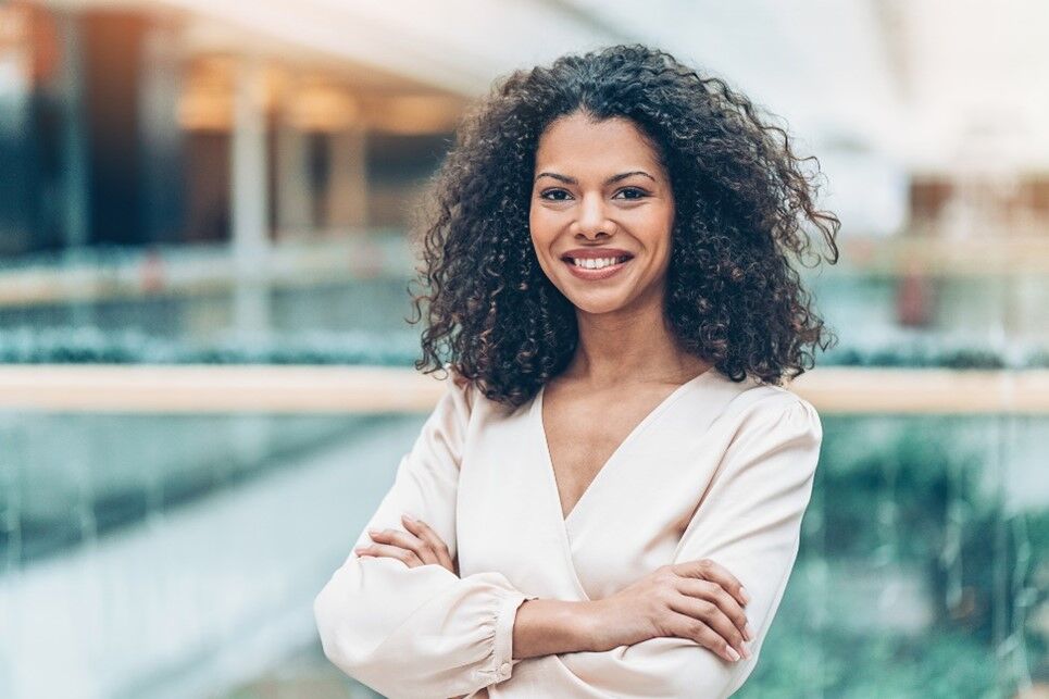 Woman with folded arms smiling and staring to camera.