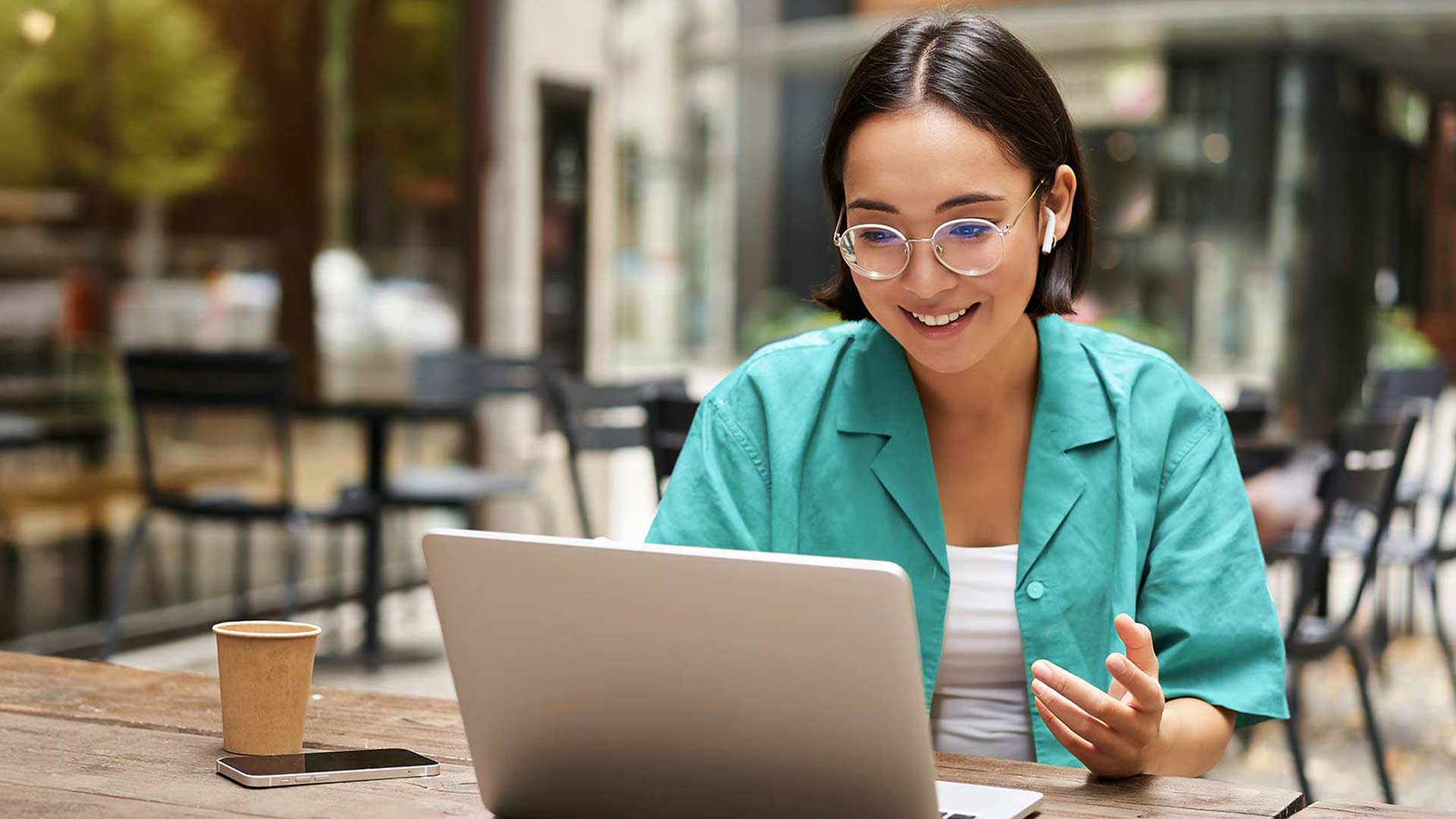 Woman sitting outside on her laptop smiling.